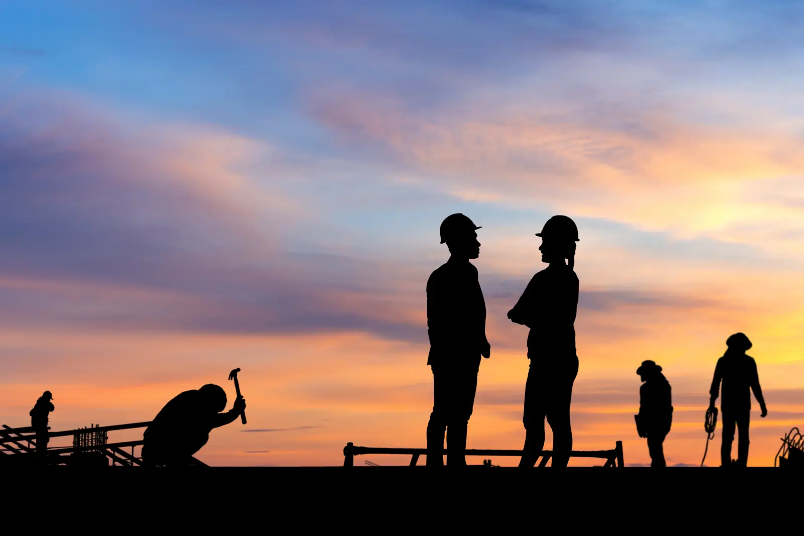 Construction crew in silhouette on a job site at sunset