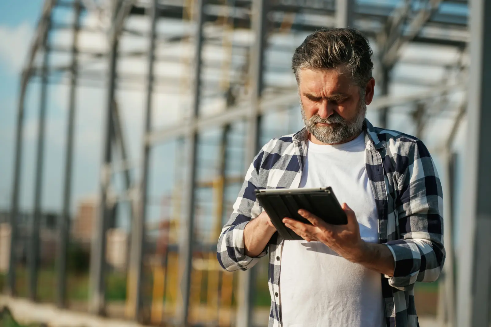 Site lead checking a tablet on a steel frame job site